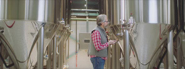 Brewery worker checking the vats alt