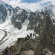 Two Climbers on Peak of Rock. Snow-Capped Mountains. Aerial View - VideoHive Item for Sale