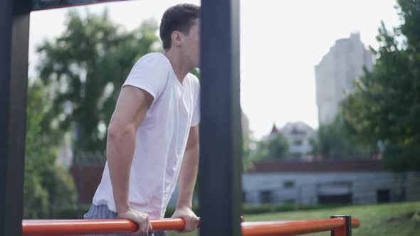 Confident Young Sportsman Working Out on Gymnastic Set in Summer Spring Park alt
