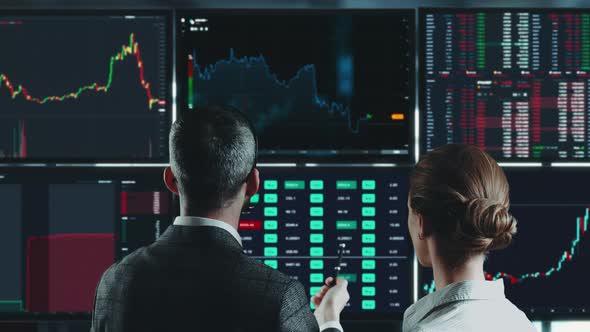 people watching multiple computer screens with charts