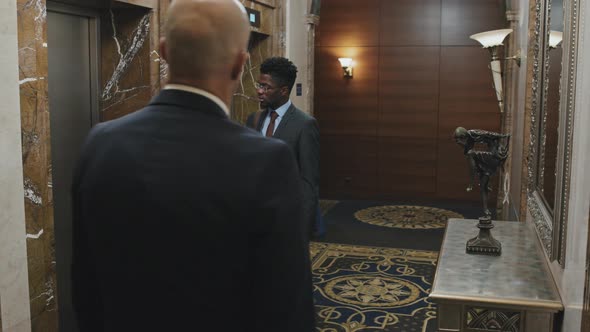 Colleagues Talking by Elevator in Business Center alt