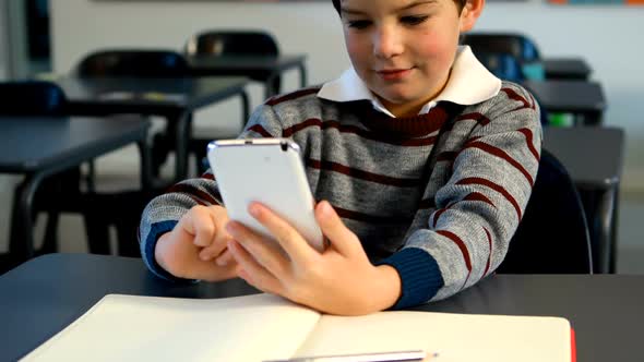 Schoolboy using mobile phone in classroom 4k alt