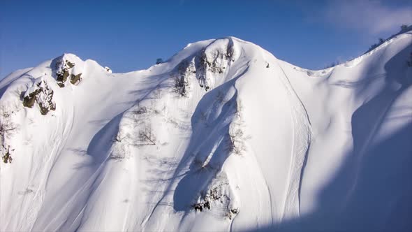 A helicopter lands to pick up skiers in the mountains. alt