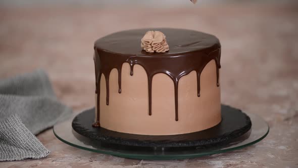 Female hands decorate a sponge cake with chocolate cream from a pastry bag.	