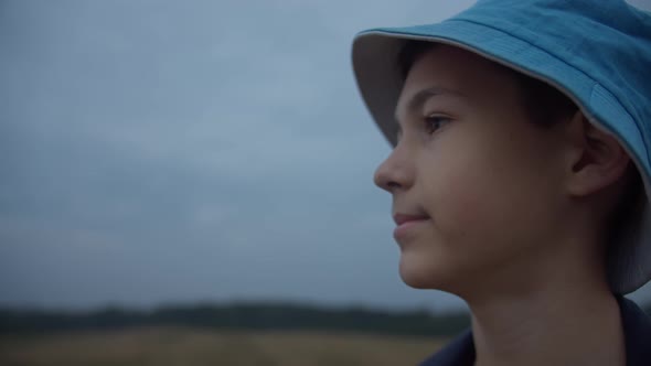 Profile of a Happy Boy in a Hat Looking Outdoors Moving Camera