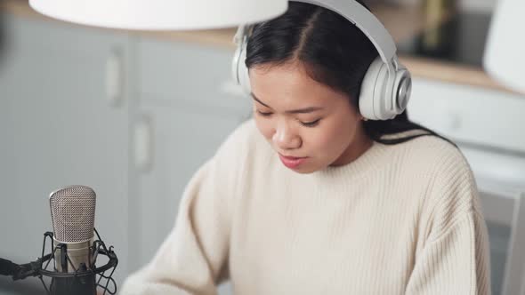 Portrait of a Asian Female Streamer in the Headphones Woman Makes a Live Podcast for Social Networks alt