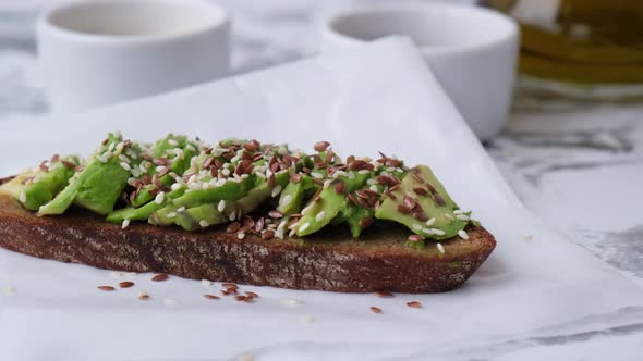 Female Hand Making Healthy Avocado Toast on Wooden Board alt