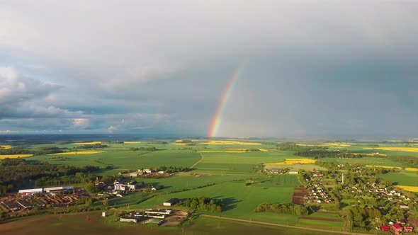 The Rainbow Over the Rape Field With Blooming Canola, During Spring, Aerial View Under Heavy Clouds alt