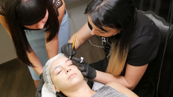 The Microblading Master Teaches His Student to Make the Correct Shape of Eyebrows on the Model