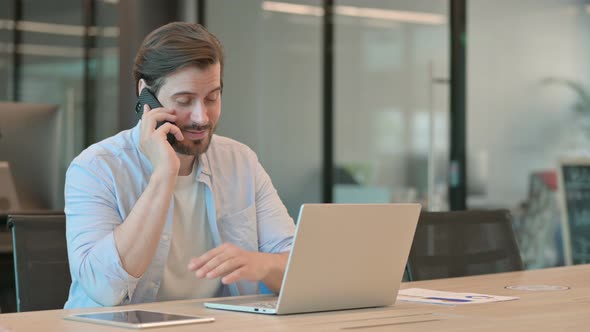 Man with Laptop Talking on Phone alt
