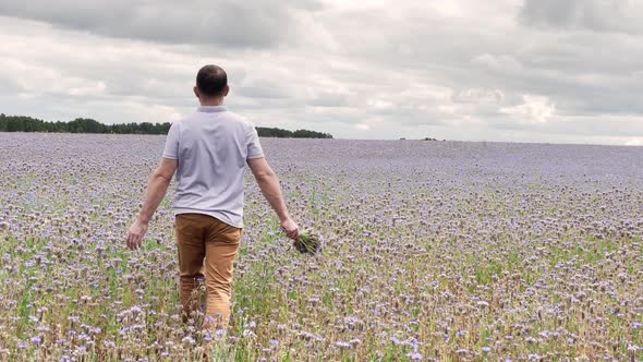man walks through a field in purple flowers alt