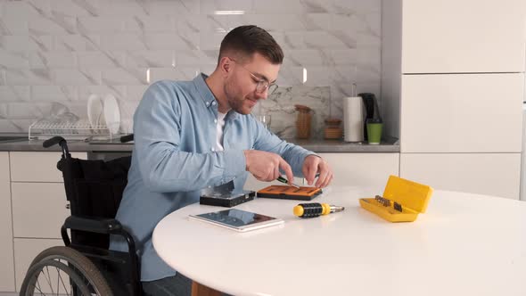 Young Disabled Man Repairing Motherboard at Kitchen alt