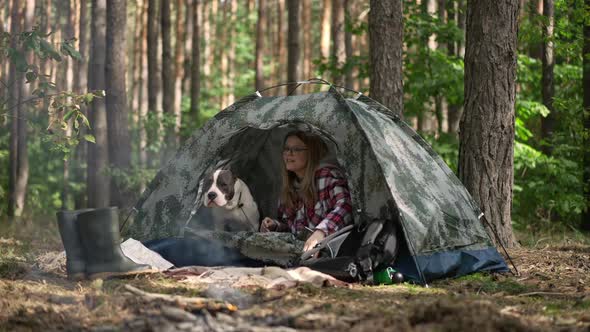 Relaxed Woman Opening Unzipping Camp Tent Stretching in the Morning in Forest with Dog alt