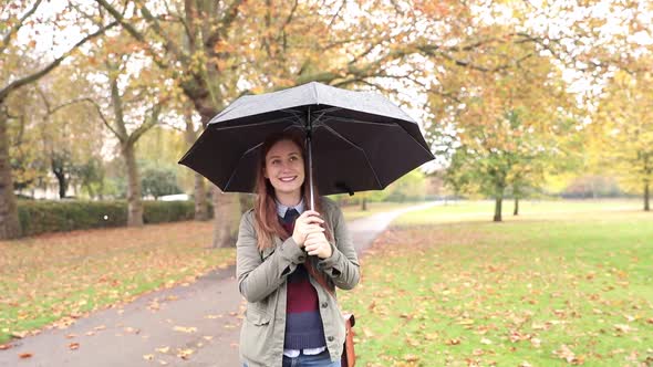 Happy woman portrait at park on a rainy day in London