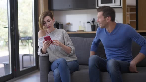 Man Entering Living Room Sitting Down on Couch As Woman Ignoring Partner Surfing Internet on alt