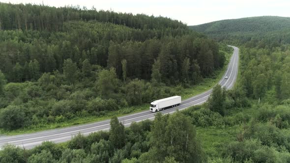 Aerial Drone View of a Truck Car Driving on a Bending Road Among Green Trees alt