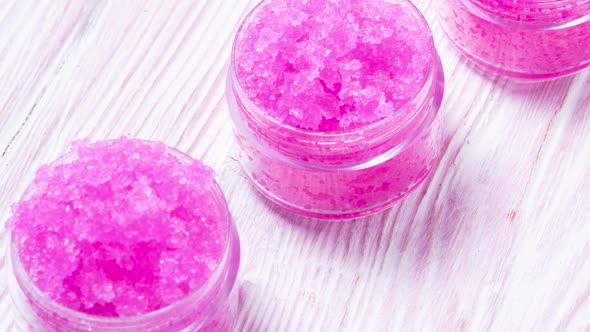 Pink homemade pil balm scrub on wooden desk