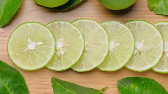 Top view limes slices on wooden with leaves.