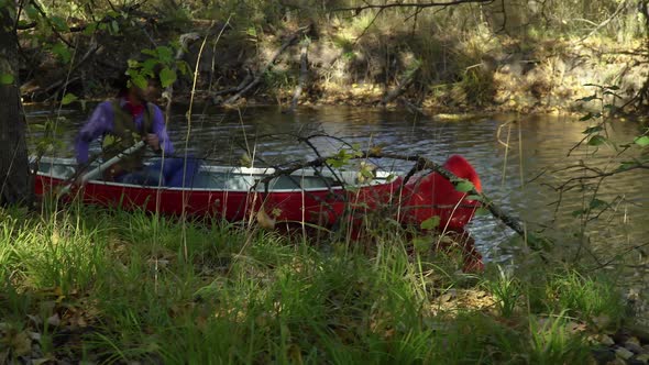 Cowboy in a Canoe Floats on the River in the Forest alt