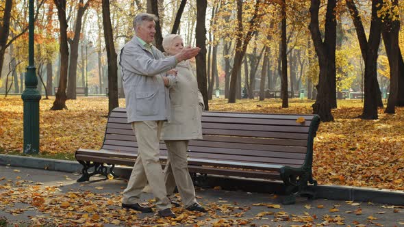 Elderly Married Couple Walking in Autumn Park Old Woman Holding Husband Hand Enjoy Conversation alt