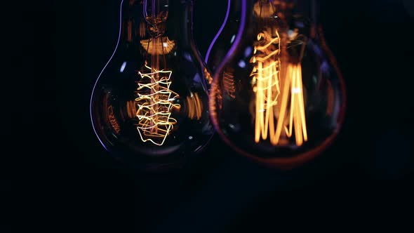 Vintage decorative light bulbs hang and shine in the dark close up.