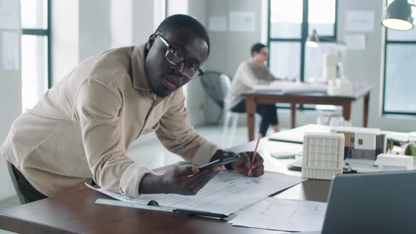 Portrait of Black Male Architect Drawing Floor Plan with Smartphone alt