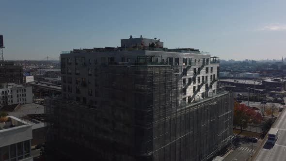 Fly Over Apartment Building with Rooftop Terraces and Scaffolding Around Facade alt