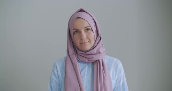 Looking at the Camera and Nodding Her Head, a Muslim Woman in a Hijab Is Talking on a Video Link and alt