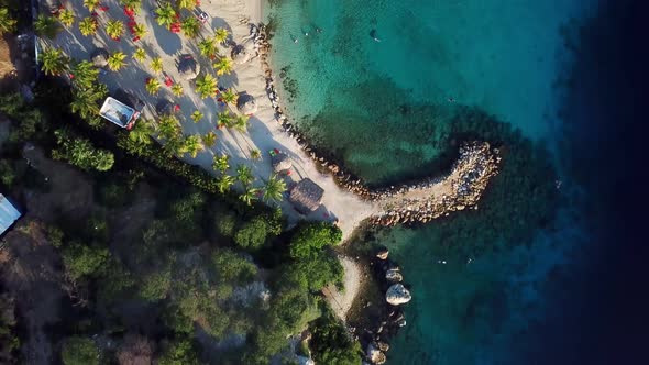 Dolly in overhead aerial view of the shore of Blue Bay beach in Curacao, Dutch Caribbean island alt