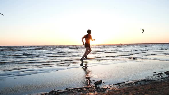 Man Running Along the Beach and Raises Hands Up at the Finish at Sunset, Slow Motion alt