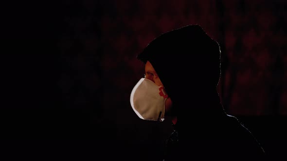 Silhouette of Man in Hood and Medical Mask Watching TV with Fake News. Pandemic alt