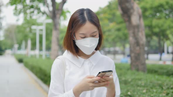 Woman wearing a protective mask using a smartphone
