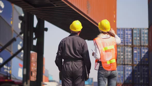 Engineer and foreman team in hardhat and safety vest control loading containers box at cargo alt