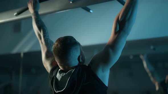 A Handsome Young Muscular Sportsman is Doing Exercise on a Fitness Machine in the Gym alt