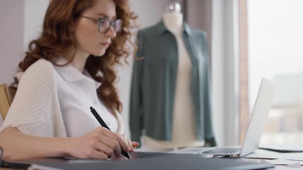 Ginger adult woman using laptop and digital tablet at work. Shot with RED helium camera in 8K alt