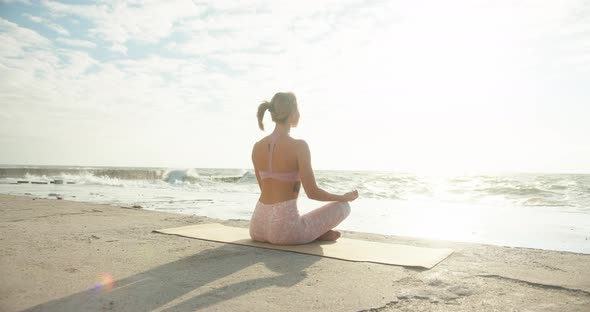 Young Woman Meditates in Lotus Pose Against Sea Terminal