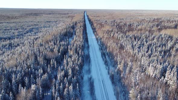 Aerial View From a Drone of a Road in the Middle of Snowcovered Trees and Snowcovered Forest on a