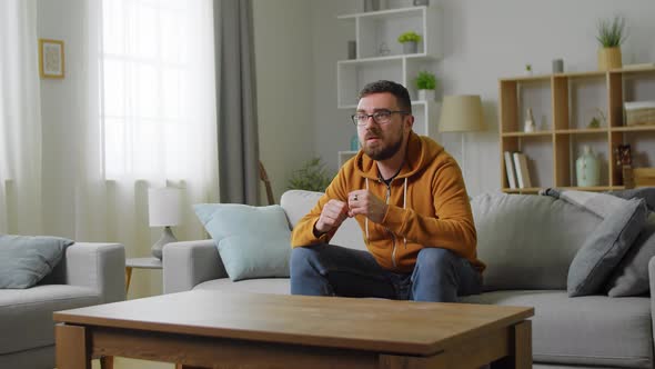 Oung Male Caucasian Sport Fan Sitting at Home on the Couch and Then Cheering Up As His Team Winning alt