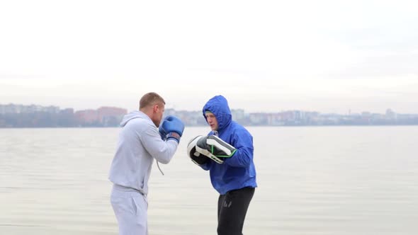 A young fighter in a gray suit runs with dumbbells in his hands and waving his arms alt
