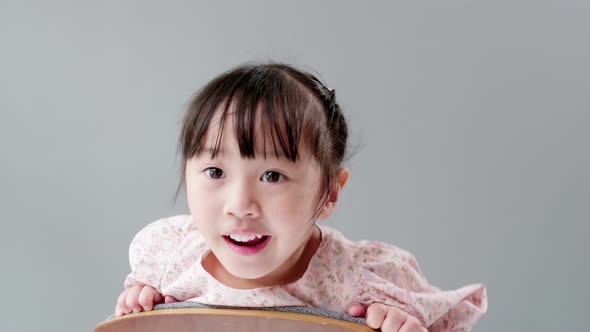 Child with hand on head looking at camera. alt