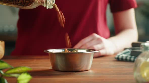 Putting Dried Dog Food in Metal Bowl Closeup Granules alt