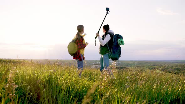 Mom and Daughter in Nature Shoot Video Blog on Camera a Selfie Stick About Tourist Trip on Mountain alt