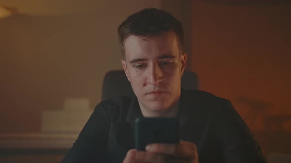 Man Typing Messages on Smartphone in Smoked Cozy Evening Room alt