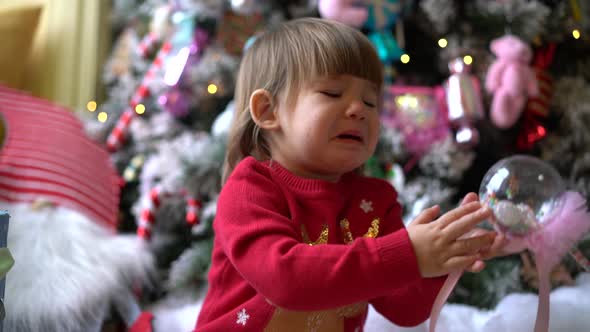 A Little Girl is Crying Near Christmas Tree a Girl in a Red Sweater is Crying alt