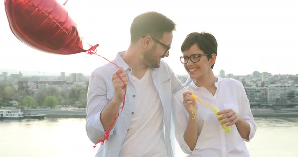 Romantic Young Couple Dating Outdoor and Blowing Bubbles