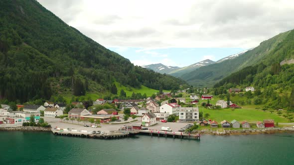 Waterfront Buildings Of Eidsdal Village With Birds Flying Over Fjord In Norway. - aerial alt