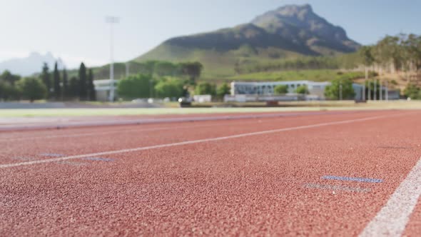 Disabled mixed race man with prosthetic legs running on race track alt