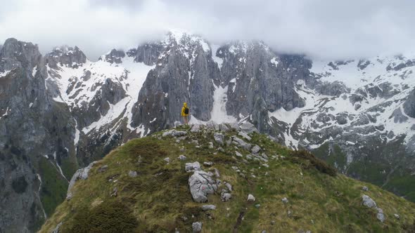 A Hiker Stands on Top of a Mountain and Looks at Snow-capped Mountains