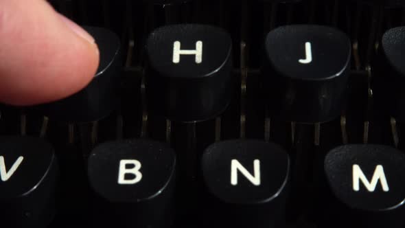 A man presses his fingers on the keys of a vintage typewriter. alt