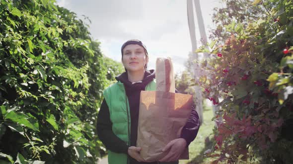 Food Delivery Person Holding Paper Bag with Food at Street Outdoors Portrait of Delivery Man alt